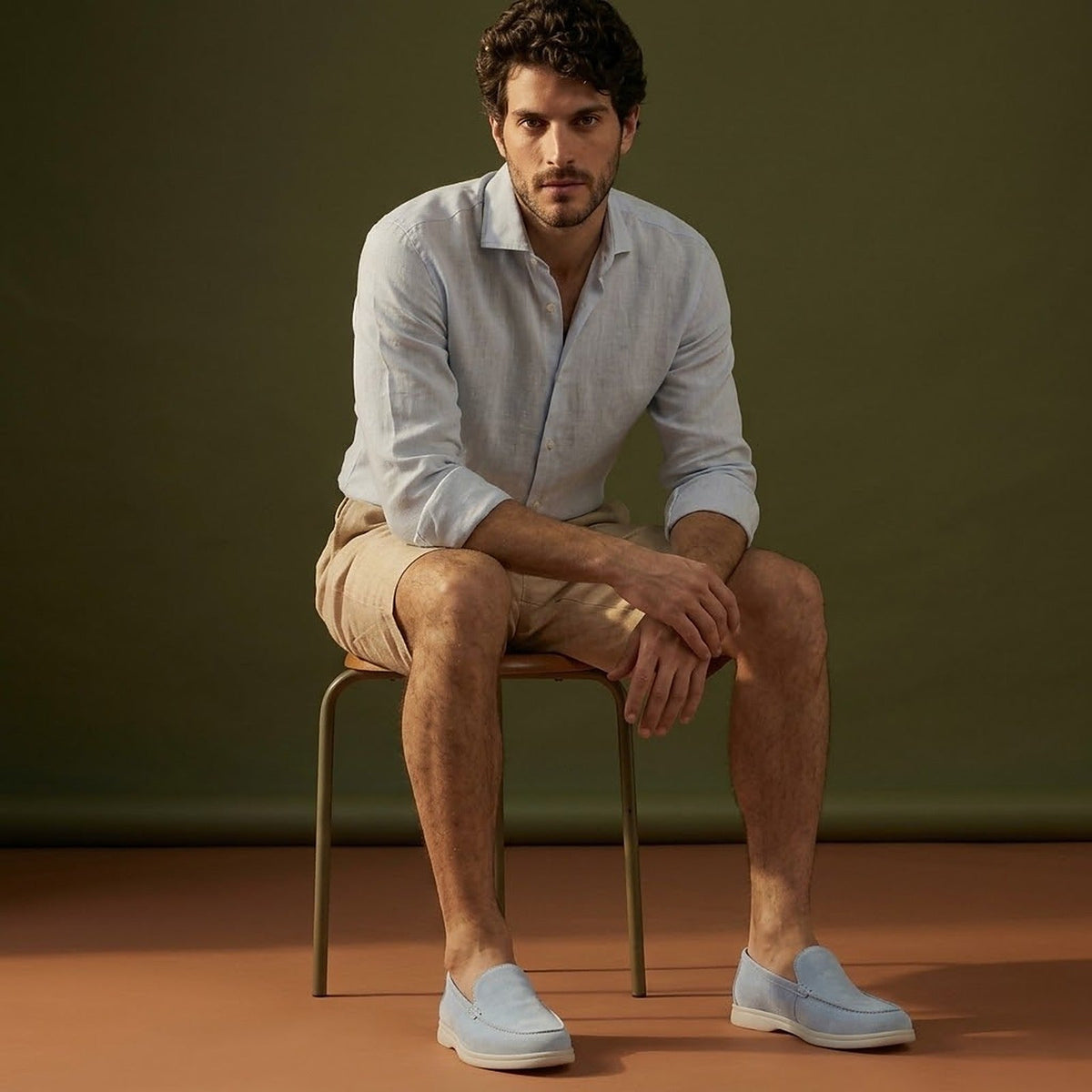 Anzio Loafer Sky, worn with linen, on a stool